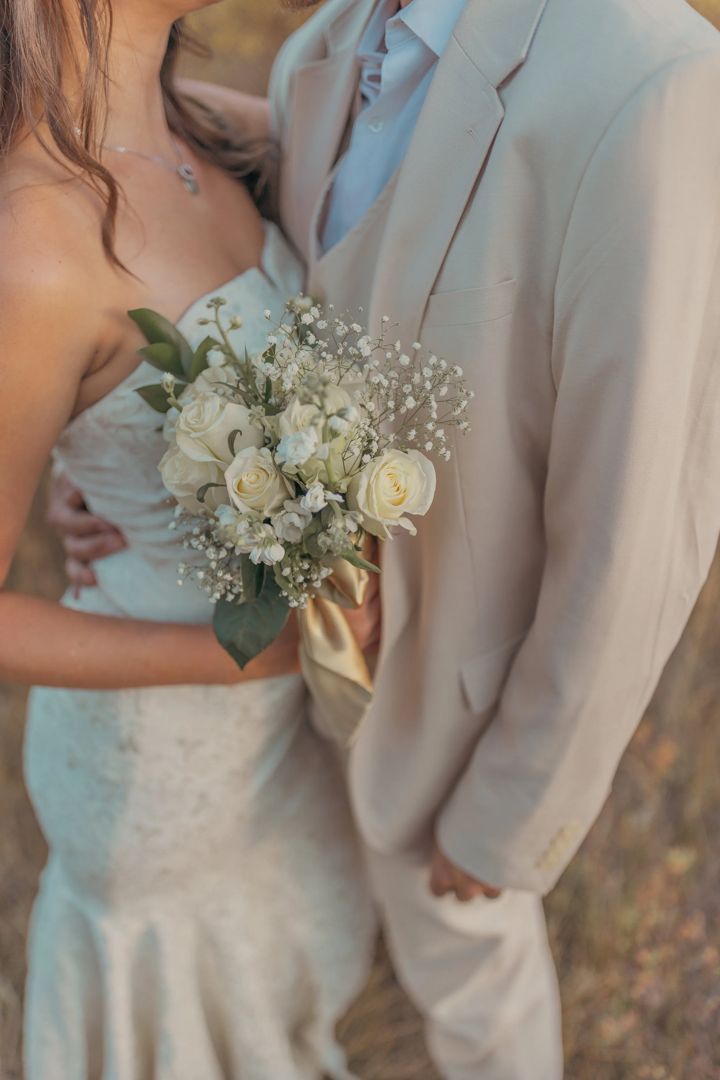 Bride holding a bouquet beside her partner in golden light