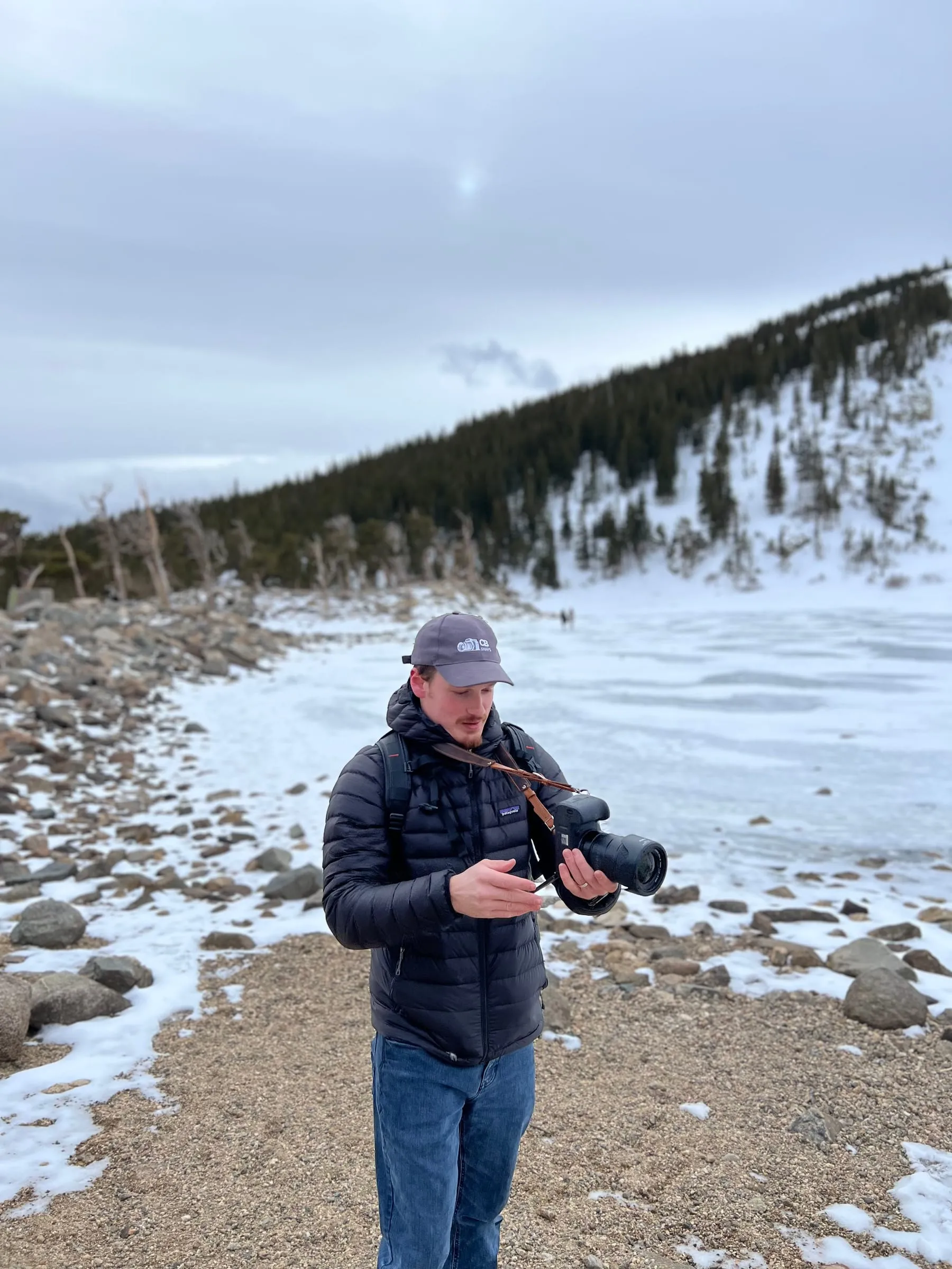 Christian looking down at the back of his camera by the lake