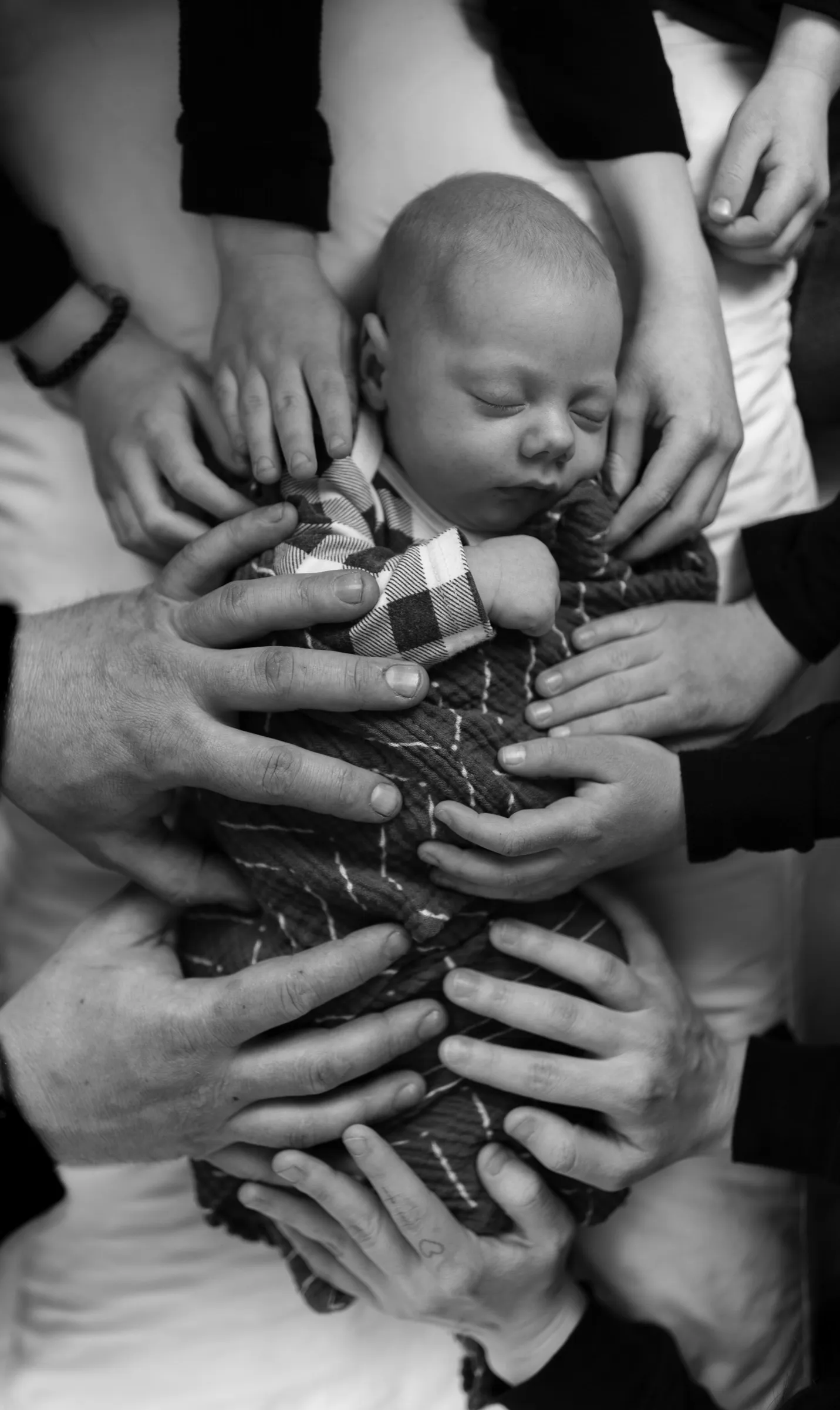 Many hands cradling a newborn