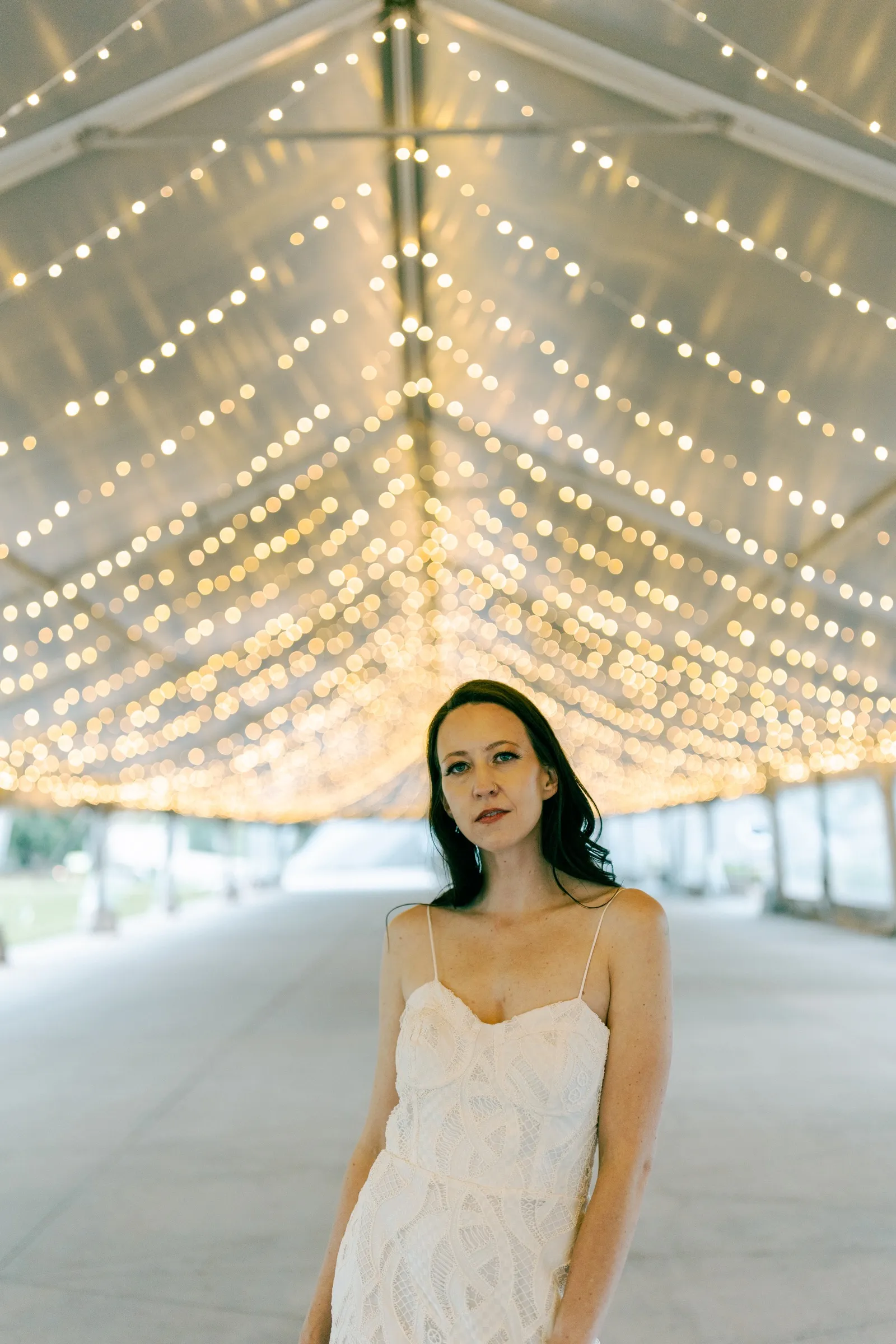 Bride standing beneath a tent ceiling strung with hundreds of lights